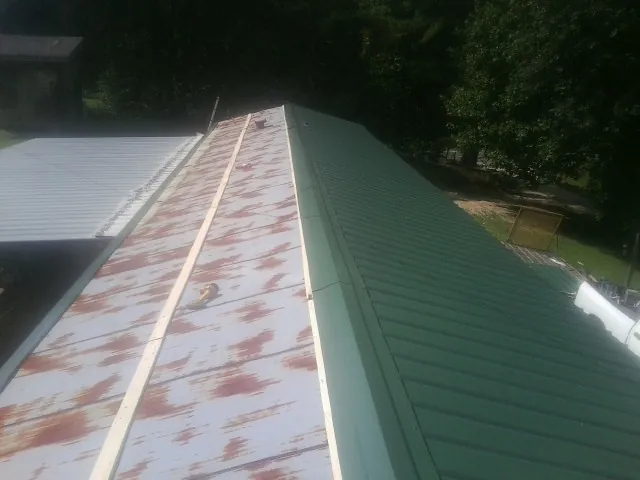 Old rusted panels beside newly installed green metal roofing — Wind Damage Roof Repair by Roofing Brothers in Gresham