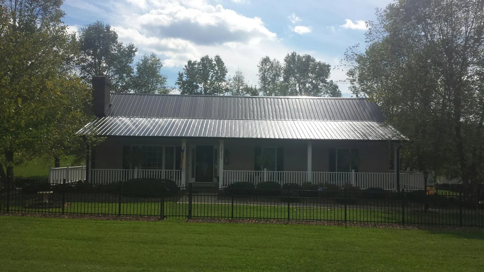 Gray metal roof on a brick ranch with a full width front porch — Gutter Guard Installation work by our crew in Gresham